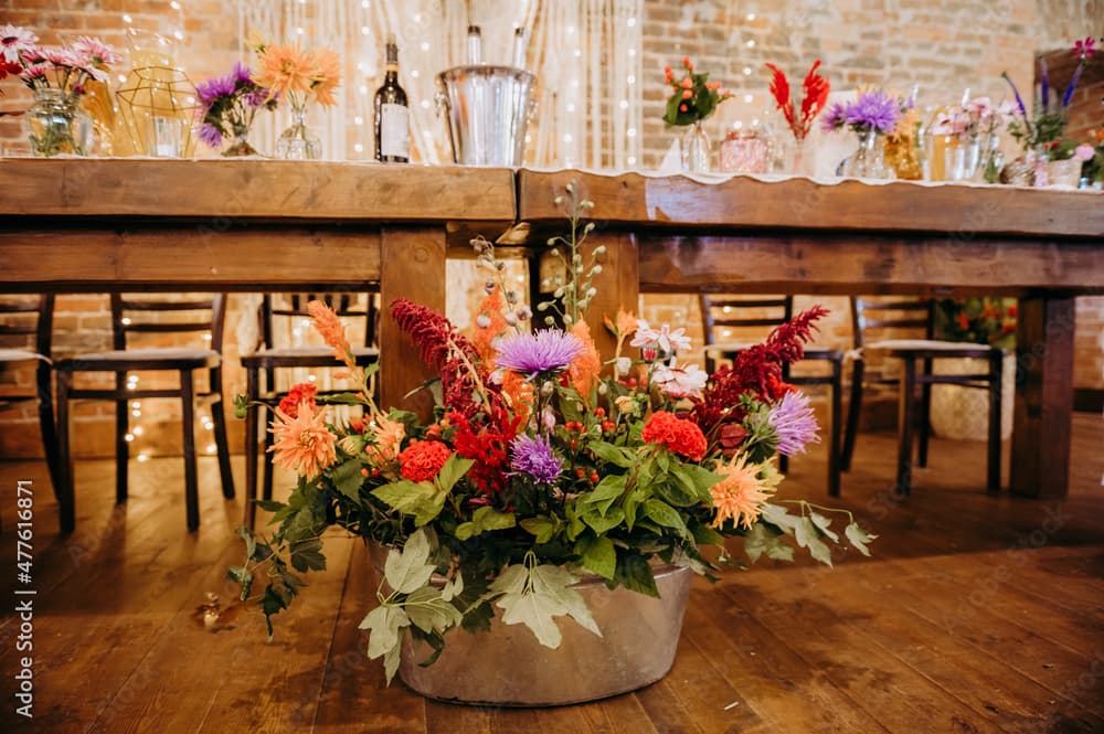Rustykalny stol weselny z kwiatami i cieplym oswietleniem.